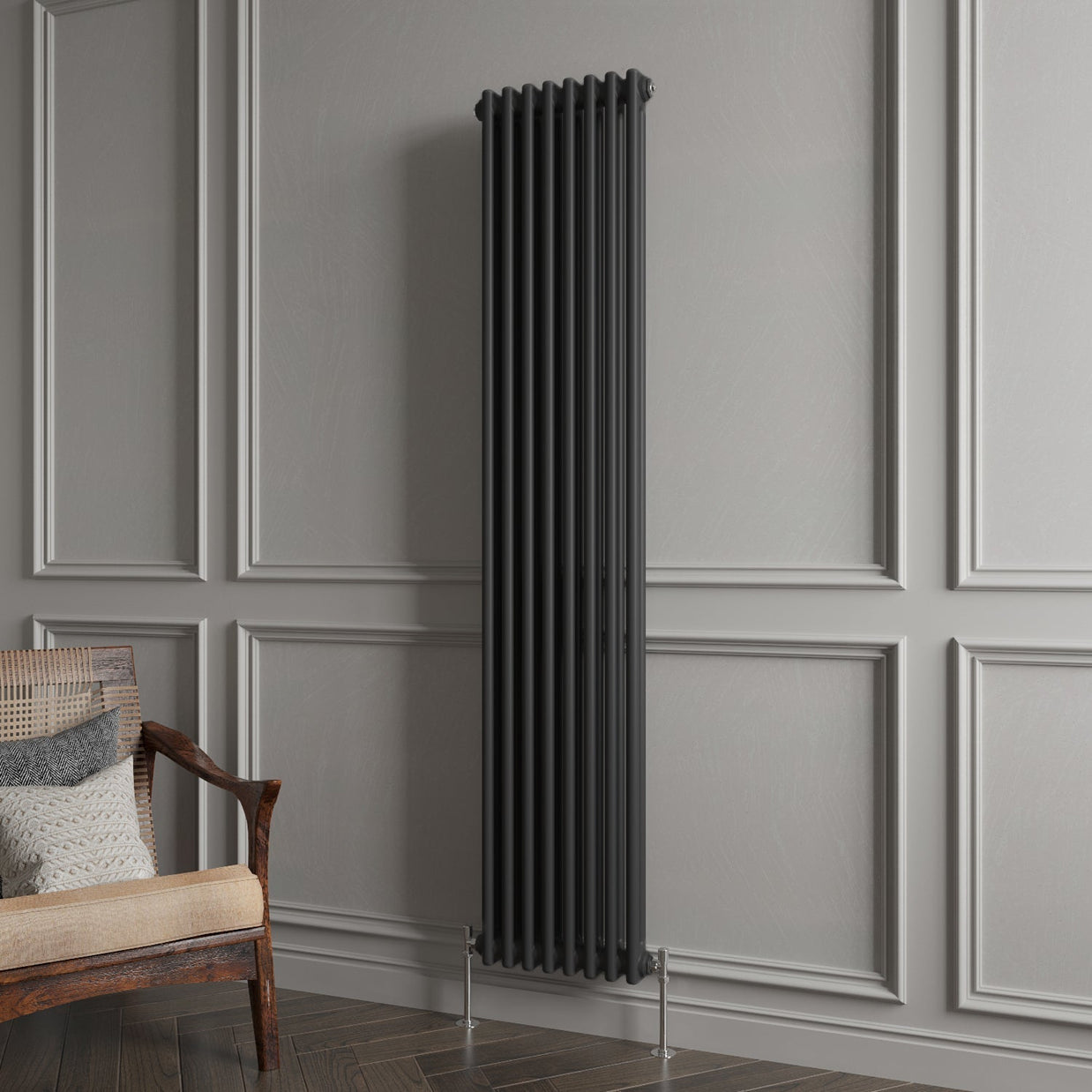 Black vertical radiator against a gray paneled wall with a wooden chair.