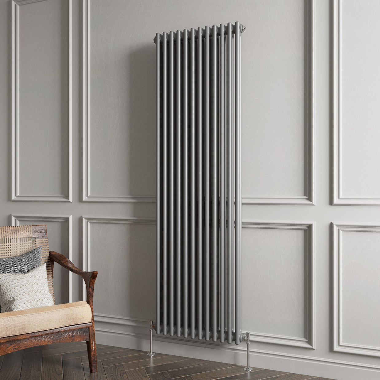 Vertical radiator on a gray paneled wall with a wooden chair and cushions.