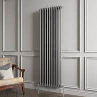 Vertical radiator on a gray paneled wall with a wooden chair and cushions.