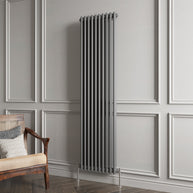 Vertical radiator on a gray paneled wall with a wooden chair.