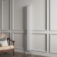 White vertical radiator against a gray paneled wall with a wooden chair.
