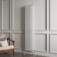 White vertical radiator against a gray paneled wall with a wooden chair.