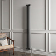 Vertical radiator against a gray paneled wall with a wooden chair.