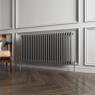 Gray radiator on a wall with wooden flooring and a chair.