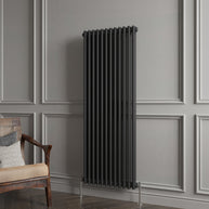 Black radiator against a gray paneled wall with a wooden chair.