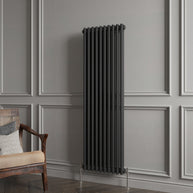 Decorative vertical radiator against a gray paneled wall with a wooden chair.