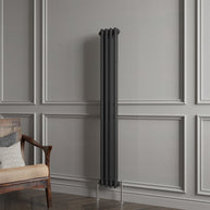 Tall black radiator against a gray paneled wall with a wooden chair.