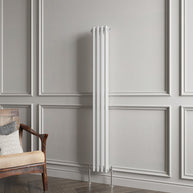 White vertical radiator against a gray paneled wall with a wooden chair.