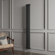 Vertical radiator against a gray paneled wall with a wooden chair.