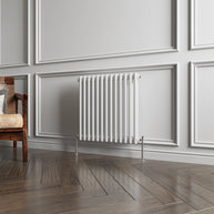 White radiator on a gray paneled wall with wooden flooring