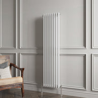 White vertical radiator on a gray paneled wall with a wooden chair.